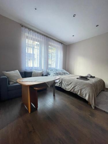 a bedroom with a bed and a table and a window at Apartament Nowy Targ in Nowy Targ