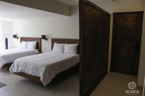 a bedroom with two beds and a door in it at ALDEA Luxury villas & suites in San Martín de las Pirámides