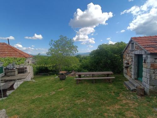 a wooden bench sitting in the grass next to a building at Kuća za odmor Milica in Vučipolje