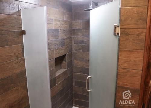 a shower door in a bathroom with a brick wall at ALDEA Luxury villas & suites in San Martín de las Pirámides
