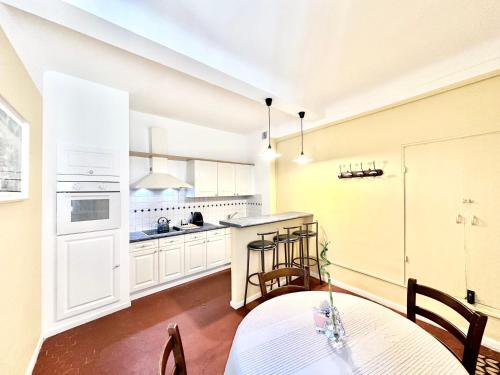 une cuisine avec des armoires blanches et une table et des chaises dans l'établissement Ersextius RL Aix-en-Provence, à Aix-en-Provence