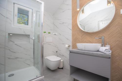 Un baño con ducha, lavabo y espejo. en APARTMANI SLAMIĆ, en Primošten