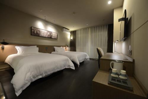 ein Hotelzimmer mit zwei Betten mit weißen Laken in der Unterkunft Jinjiang Inn Yancheng Dongtai Municipal Government in Dongtai