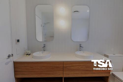 a bathroom with two sinks and two mirrors at Akuna 3 in Thredbo