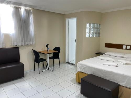 une chambre d'hôtel avec un lit, une table et des chaises dans l'établissement Hotel Piramide St. Antonio de Jesus, à Santo Antônio de Jesus