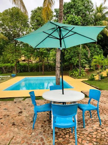 a table and chairs with an umbrella next to a pool at Encantadora Villa Aquarine in Buena Vista