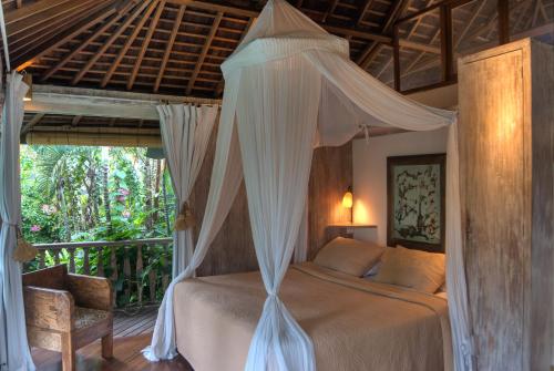 a bedroom with a canopy bed and a chair at Villa Istimewa in Seminyak