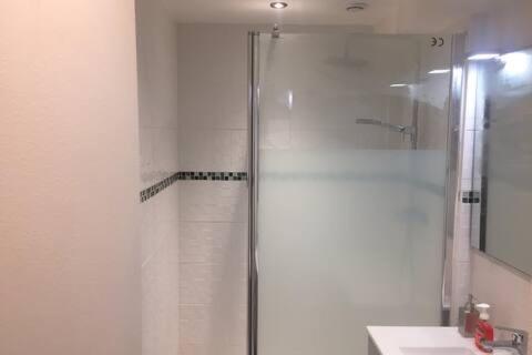 une douche avec une porte vitrée dans une salle de bain dans l'établissement Résidence proche gare RER, à Noisy-le-Grand