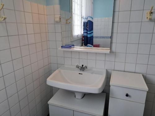 une salle de bain blanche avec un lavabo et un miroir dans l'établissement House in Treompan near Sandy Beach, à Ploudalmézeau