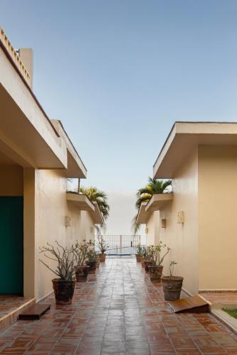 a walkway between two buildings with potted plants at Bungalows Las Arenas in San Patricio Melaque