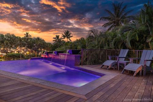 a pool on a deck with chairs and a sunset at Kaanapali Hini NEW POOL - FULLY REMODELED - Across the Street From Kaanapali Beach in Lahaina