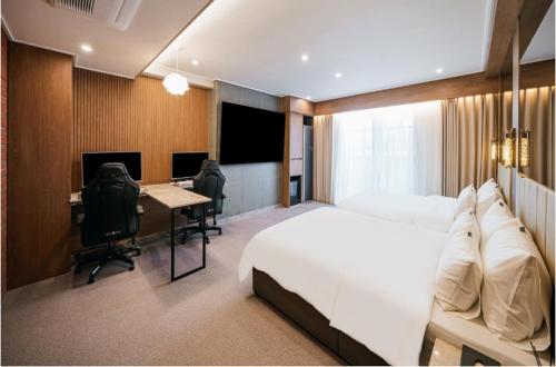 a bedroom with a bed and a desk with a computer at Brown Dot Hotel Andong Ok-dong in Andong