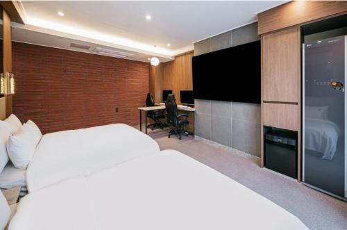 a bedroom with a large white bed and a desk at Brown Dot Hotel Andong Ok-dong in Andong