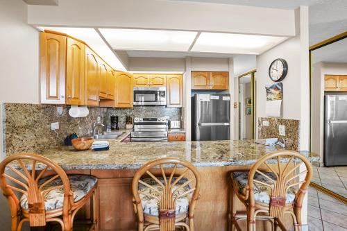 a kitchen with wooden cabinets and a counter with chairs at Papakea's Finest - OCEAN VIEW Luxury 2 bedroom 2 bath - AC IN EVERY ROOM in Kahana