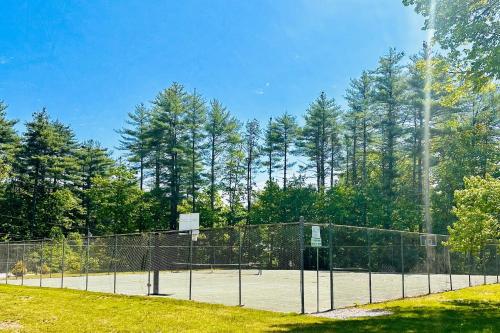 a tennis court with a fence and trees at Crescent Corner in Waterboro