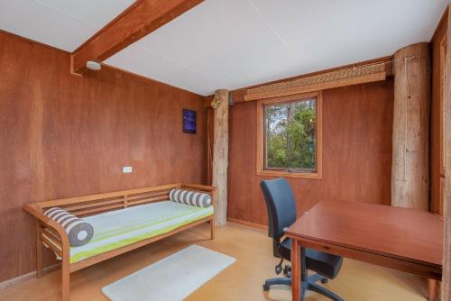 Un dormitorio con una cama, un escritorio y una mesa. en 129 Murrah, en Bermagui