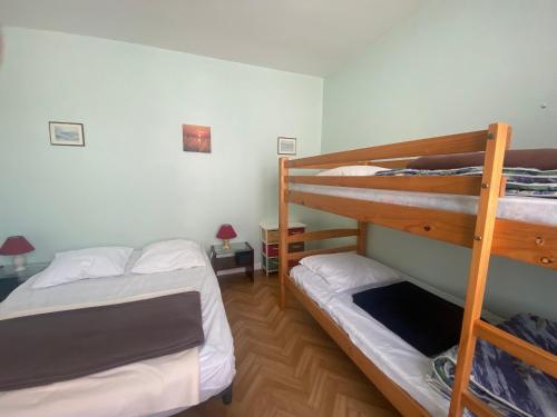 Ce dortoir comprend 2 lits superposés et 2 tables. dans l'établissement Charmant T2 avec Terrasse Privée, à 600m Plage et Commerces, La Tranche-sur-Mer - FR-1-22-278, à La Tranche-sur-Mer