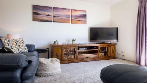 a living room with a television on a wooden entertainment center at 54 Bunga Street in Bermagui