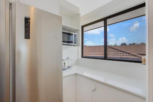 een keuken met witte kasten en een raam bij 35 Scenic Drive in Bermagui