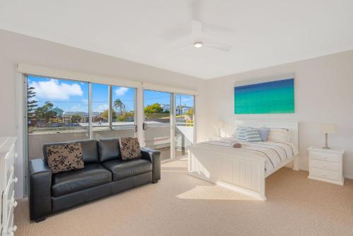a bedroom with a couch and a bed and a window at seascape 5 in Bermagui