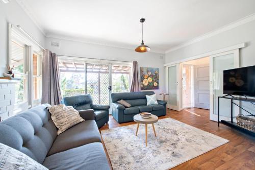 a living room with a couch and a tv at Rosewood Cottage - Stroll to Central, Cosy Escape in Dubbo