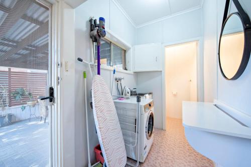 ein Badezimmer mit Waschmaschine und Waschbecken in der Unterkunft Rosewood Cottage - Stroll to Central, Cosy Escape in Dubbo
