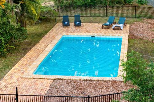 una piscina con due sedie blu e un piscina con piscina di Lakeview Cottage in Mooloolah Valley a Mooloolah