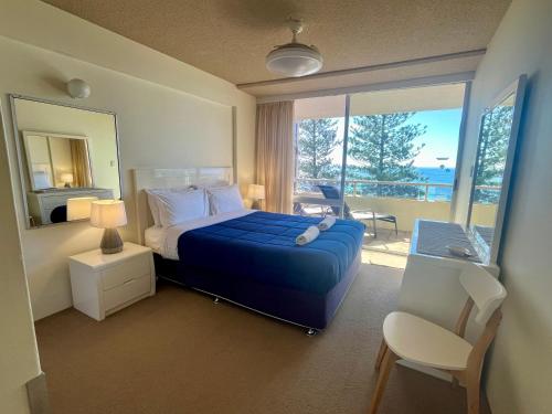 a bedroom with a blue bed and a balcony at Park Towers-Goodwin Towers Holiday Units in Gold Coast