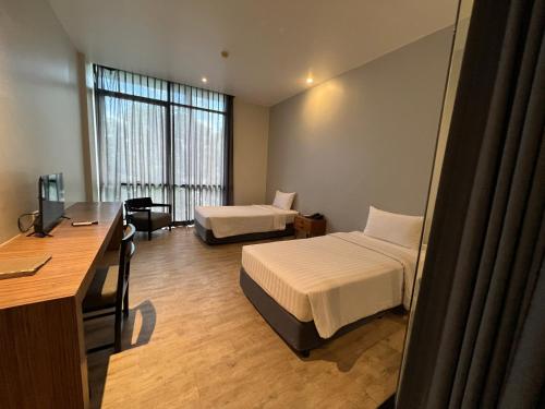 a hotel room with two beds and a desk and a desk at Vismaya Suvarnabhumi Hotel in Lat Krabang