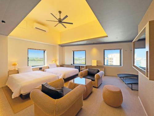 a hotel room with two beds and chairs at hotel androoms Naha Port in Naha