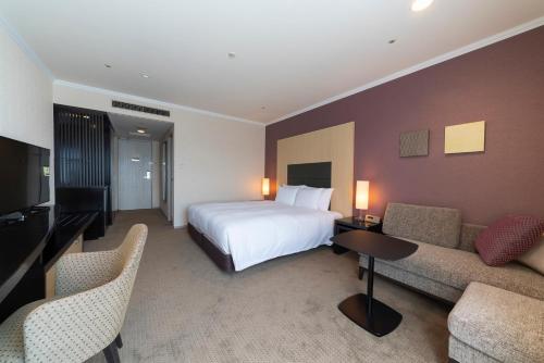 a large hotel room with a bed and a couch at Hotel Associa Toyohashi in Toyohashi