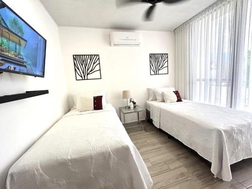two beds in a white room with a tv at Elegante condominio En Residenza Con vista al Merendon in San Pedro Sula