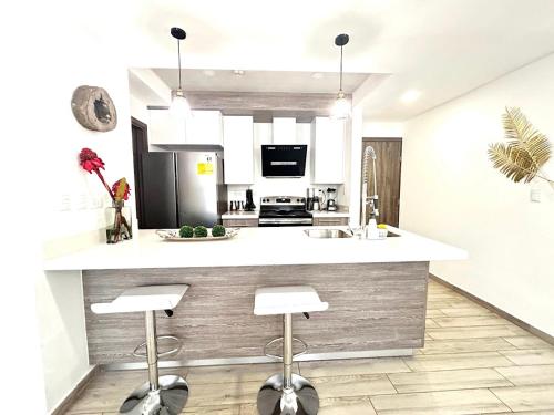 a kitchen with a counter with stools in it at Elegante condominio En Residenza Con vista al Merendon in San Pedro Sula