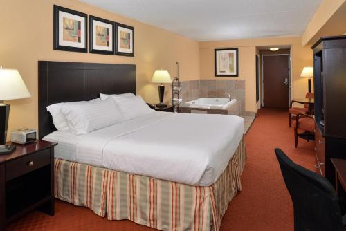 a hotel room with a large bed and a bathroom at Holiday Inn Martinsburg by IHG in Martinsburg