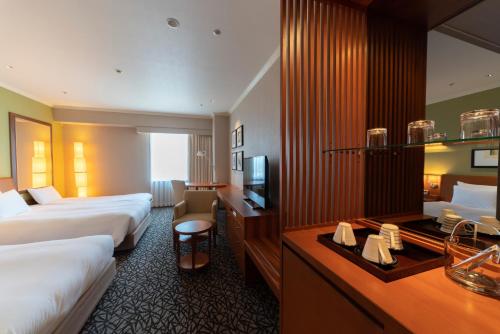a hotel room with two beds and a television at Hotel Associa Toyohashi in Toyohashi