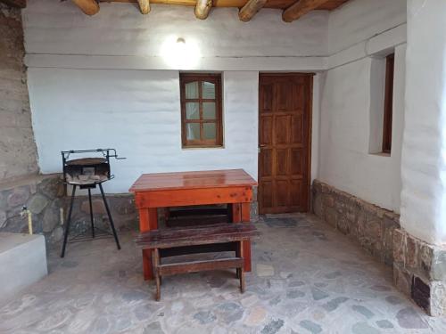 Una habitación con una mesa de madera y una puerta de madera. en CABAÑA SOLIS, en Tilcara