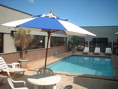 a blue and white umbrella next to a swimming pool at Lindo Apto Flat Aconchegante e Mobiliado em Campinas !!! in Campinas