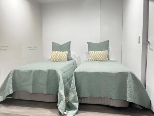 2 camas con mantas verdes y almohadas en una habitación en Circle on Cavil Holidays Gold Coast, en Gold Coast