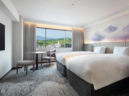 a hotel room with two beds and a desk and a window at Grand Mercure Nara Kashihara in Kashihara