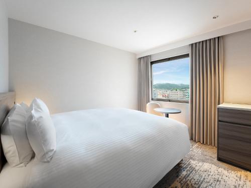 a hotel room with a white bed and a window at Grand Mercure Nara Kashihara in Kashihara