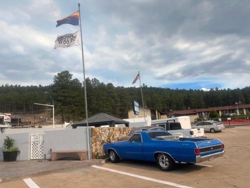 a blue truck parked in a parking lot with flags at El Rancho Motel in Williams