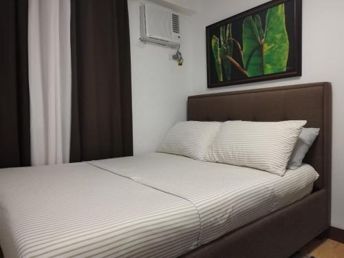 a bed in a room with a picture on the wall at Homestay Arezzo Place Davao - Building 9 in Davao City