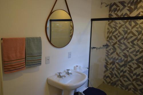 a bathroom with a sink and a mirror and a shower at Apartamento no coração de Petrópolis in Petrópolis