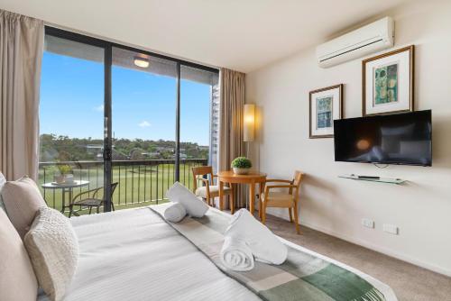 a bedroom with a bed and a flat screen tv at Moonah Links Apartments - Fairway Views, Golf, Hot Springs in Fingal