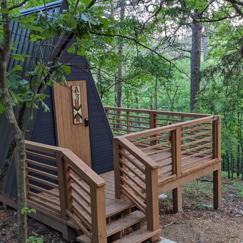 a cabin in the woods with a wooden ramp and a door at Loblolly Pines Adventure Aframe #2 in Eureka Springs