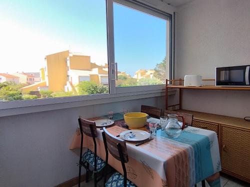une salle à manger avec une table et une fenêtre dans l'établissement Confortable T2 à Narbonne Plage - 28m2, Proche Mer, 4 Pers, Tout Équipé - FR-1-795-9, à Narbonne