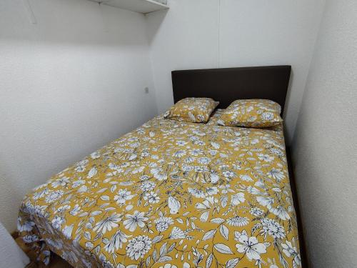- une chambre avec un lit doté d'une couverture jaune et d'oreillers dans l'établissement Confortable T2 à Narbonne Plage - 28m2, Proche Mer, 4 Pers, Tout Équipé - FR-1-795-9, à Narbonne