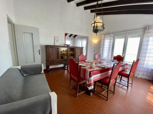 une salle à manger avec une table et des chaises rouges dans l'établissement Narbonne-Plage : T4 en 1ère ligne, 7P, balcon, parking, accès plage direct - FR-1-795-6, à Narbonne