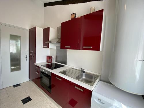 une petite cuisine avec des armoires rouges et un évier dans l'établissement Narbonne-Plage : T4 en 1ère ligne, 7P, balcon, parking, accès plage direct - FR-1-795-6, à Narbonne