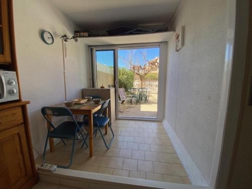 une cuisine avec une table et une porte donnant sur une terrasse. dans l'établissement Coquet T2 à Narbonne Plage - Cour arborée, Parking, Proche plage et commerces, 4 pers. - FR-1-795-14, à Narbonne